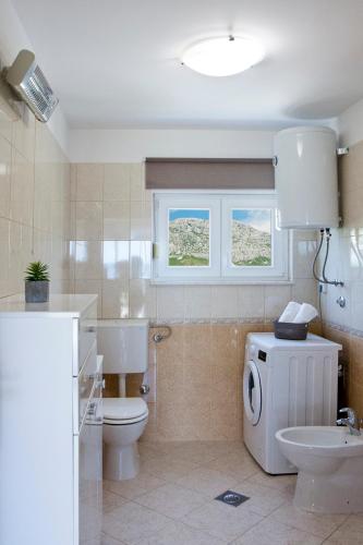 a bathroom with a toilet and a sink and a window at Apartment Noel in Kaštela