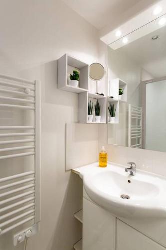 une salle de bain blanche avec un lavabo et un miroir dans l'établissement Quiet, Cozy, Design Apartment in Paris, à Paris