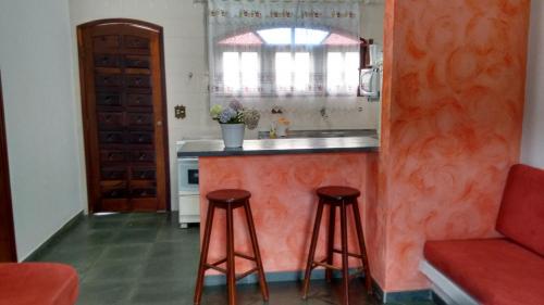 a kitchen with a counter and two stools at Mata Atlântica Chalés - Praia da Lagoinha, Ubatuba - SP in Ubatuba