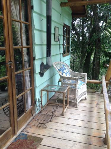 a porch with two wicker chairs and a table at Chales Bamboo Jungle in Petrópolis