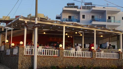um restaurante com pessoas sentadas em mesas em frente a um edifício em Hotel De Luna em Ksamil