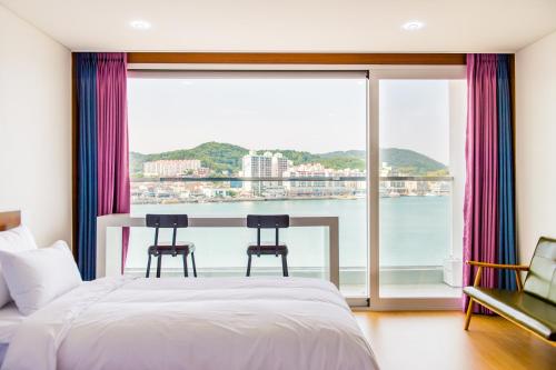 a bedroom with a large window with a view of the water at Fortuna Hotel in Tongyeong