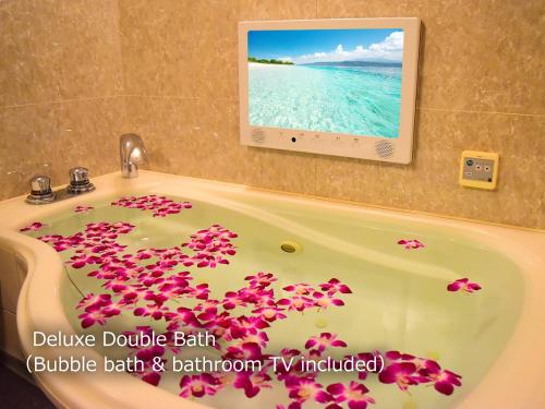 a bath tub filled with pink flowers in a bathroom at Hotel BaliAn Resort Yokohama Kannai - Adult Only in Yokohama