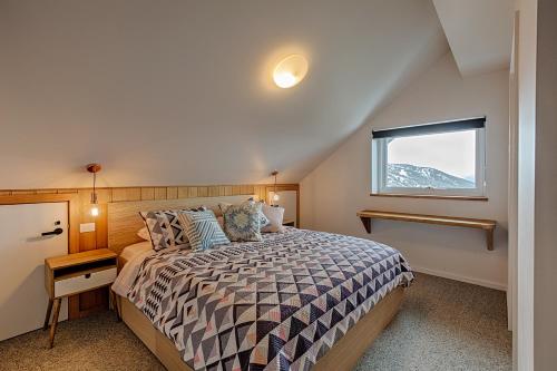 a bedroom with a large bed and a window at Le Chalets- King of the mountain- sleeps 18 by ABM in Falls Creek