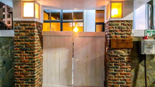 a wooden door in a room with a brick wall at Gather in Tainan