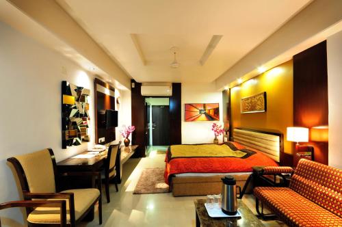 a bedroom with a bed and a table and chairs at Hotel Surabhi Regency in Anand