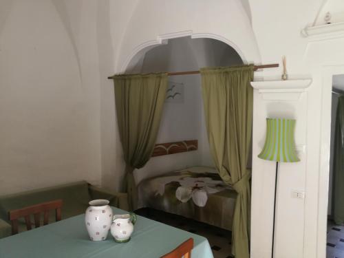 オストゥーニにあるCasa La Chicca di Ginaのテーブル、ベッド、緑のカーテンが備わる客室です。