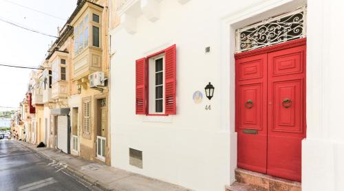 een rode deur aan de zijkant van een gebouw bij House of Pomegranates in Sliema