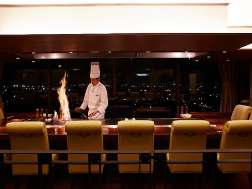 a chef standing behind a bar in a restaurant at Hotel New Otani Takaoka in Takaoka
