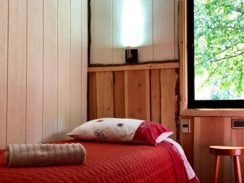 a bedroom with a bed with a pillow and a window at Cabañas Peumayén Neltume in Neltume