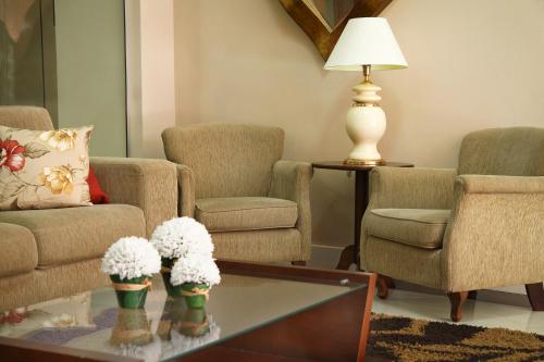 a living room with two chairs and a coffee table with flowers at klein Ville Esteio Br in Esteio