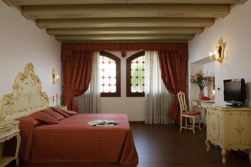 a bedroom with a bed with a red blanket and two windows at Hotel La Residenza in Venice