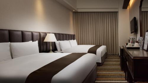 a hotel room with two beds and a desk at Urban Hotel33 in Kaohsiung