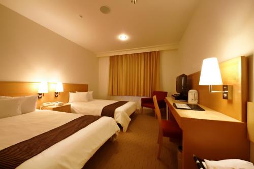 a hotel room with two beds and a desk at Welco Narita in Narita