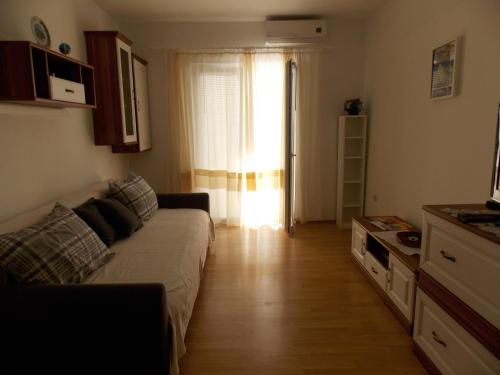 a living room with a couch in front of a window at Rocco apartments in Pag