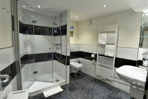 a bathroom with a shower and a toilet and a sink at Hotel Stadt Hamburg in Heiligenhafen