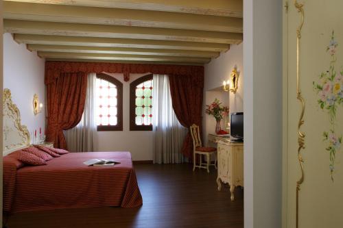 a bedroom with a bed and two windows and a table at Hotel La Residenza in Venice