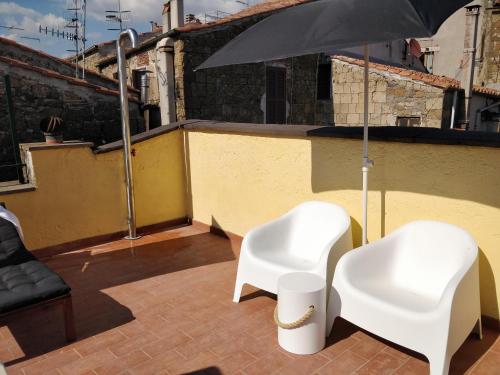 two white chairs and an umbrella on a roof at Casa Messi in Pitigliano
