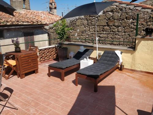 a patio with two benches and an umbrella at Casa Messi in Pitigliano
