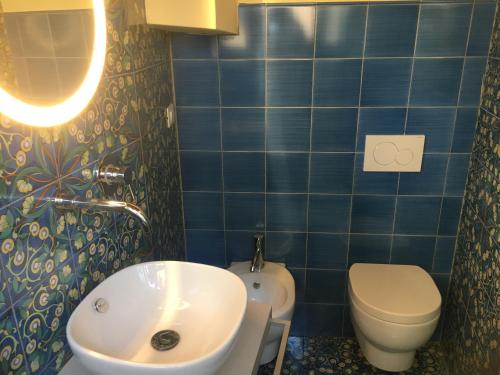 a blue tiled bathroom with a sink and a toilet at Vicolo del Geppone in Lucca