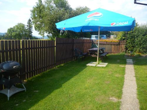 a blue umbrella in a yard with a fence at Pension Pugner in Vysoké nad Jizerou