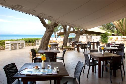 patio ze stołami i krzesłami oraz oceanem w obiekcie Torre San Vito Hotel Villaggio w mieście Gaeta