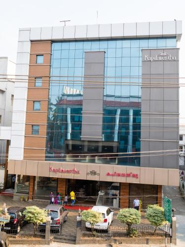 a building with cars parked in front of it at Hotel Kapilavasthu in Palakkad