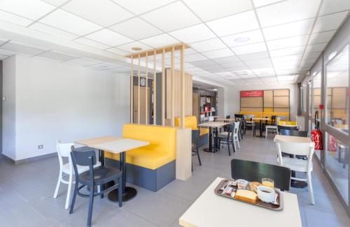 a dining area with tables and chairs in a restaurant at B&B HOTEL CHAMBERY La Cassine in Chambéry