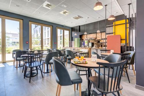 a restaurant with tables and chairs in a cafeteria at B&B HOTEL Paris Sud Chatenay Malabry in Châtenay-Malabry
