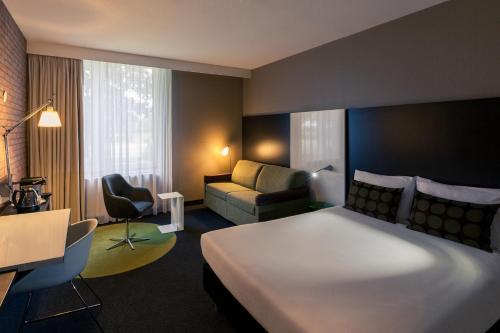 a hotel room with a large bed and a couch at Mercure Hotel Zwolle in Zwolle