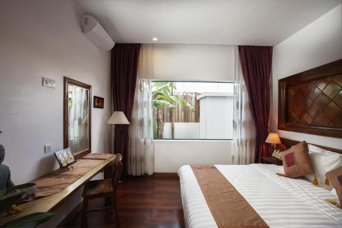 a bedroom with a bed and a desk and a window at Boravin House in Siem Reap