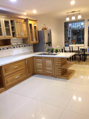 a kitchen with wooden cabinets and a kitchen with a table at Jolie House in Da Lat
