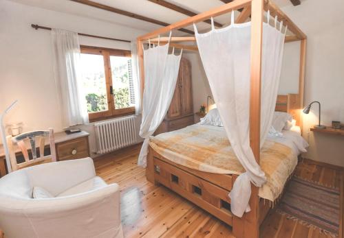 a bedroom with a canopy bed and a chair at Can Caponet in Lliçà d'Amunt
