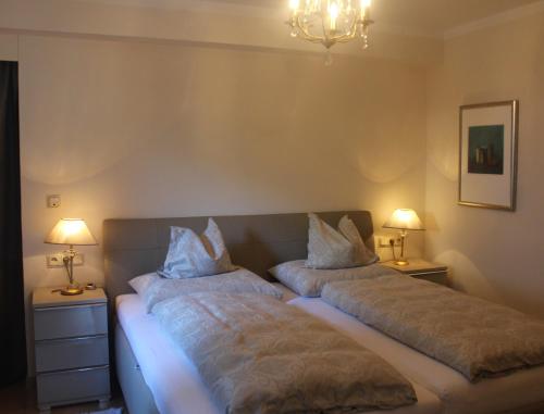 two beds in a bedroom with two lamps on tables at Villa Falkner in Tirolo