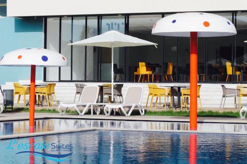 two umbrellas and chairs next to a swimming pool at L'escale Suites Résidence Hôtelière By 7AV HOTELS in Mohammedia