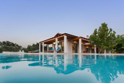 une villa avec une piscine en face d'une maison dans l'établissement Aneli Luxury Villas-Villa Elissavet, à Áyios Kírikos
