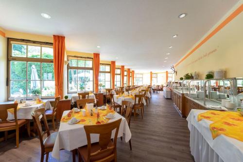 un restaurante con mesas y sillas blancas y ventanas en Hotel Goldener Hirsch en Suhl