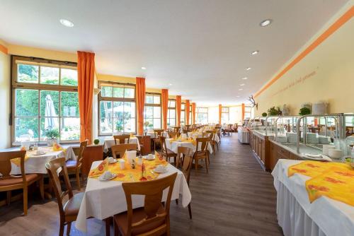 un restaurante con mesas y sillas blancas y ventanas en Hotel Goldener Hirsch, en Suhl