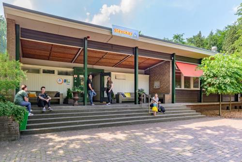 a group of people sitting on steps outside of a building at Stayokay Hostel Apeldoorn - Fully renovated March 2026 in Apeldoorn