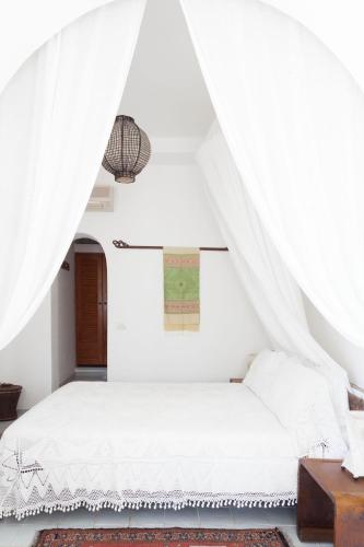a bedroom with a white bed with a canopy at Quartara Boutique Hotel in Panarea
