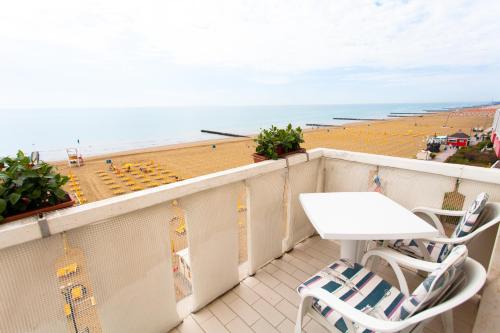 a balcony with a table and chairs and a beach at Hotel Villa Sorriso in Lido di Jesolo