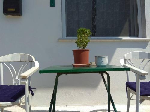 een groene tafel met een potplant en twee stoelen bij Asia's place in Kavala
