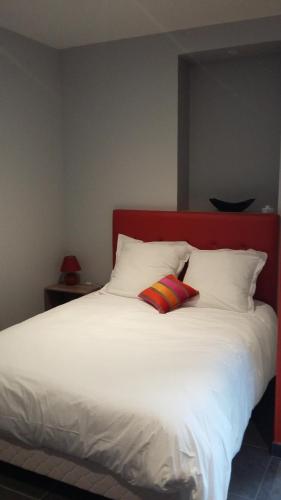 a white bed with two pillows and a red headboard at Le Logis d'Isabelle in Argentan