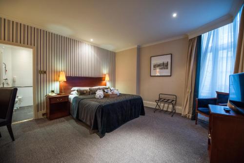 a hotel room with a bed and a television at Cairn Hotel in Harrogate