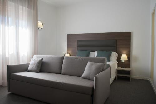 a living room with a couch in front of a bed at Hotel Villa Sorriso in Lido di Jesolo