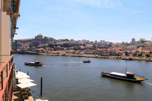 a boat traveling down a river next to a city at Oporto Home - River Front in Porto
