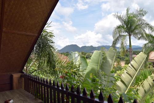 a balcony with a view of palm trees and mountains at Homestay Chiangrai in Chiang Rai