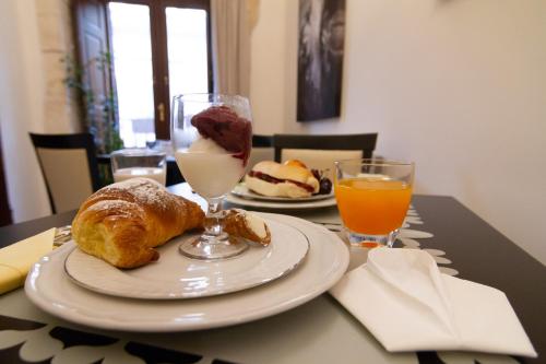 a table with a plate of pastries and orange juice at Palazzo Tasca in Noto