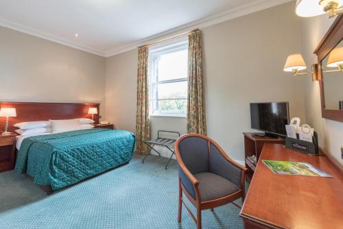 a hotel room with a bed and a desk and a television at Cairn Hotel in Harrogate