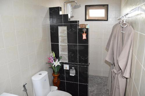 a bathroom with a toilet and a black tile wall at Homestay Chiangrai in Chiang Rai